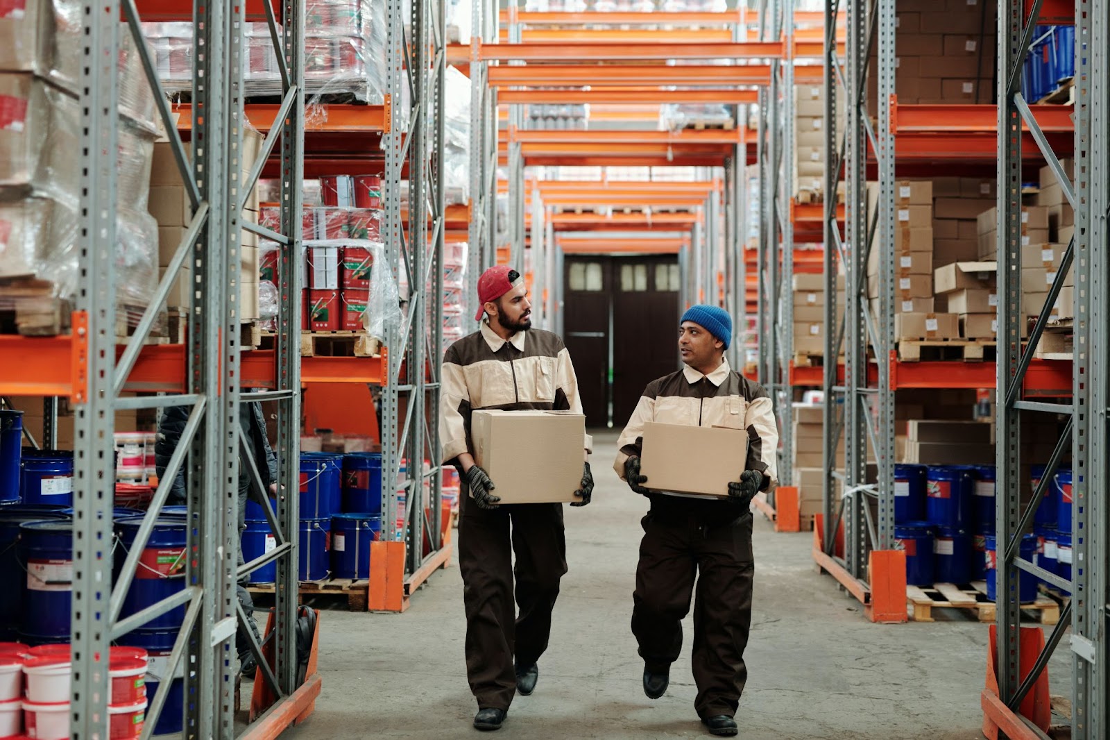 Two warehouse associates carry SKUs through the picking shelves 